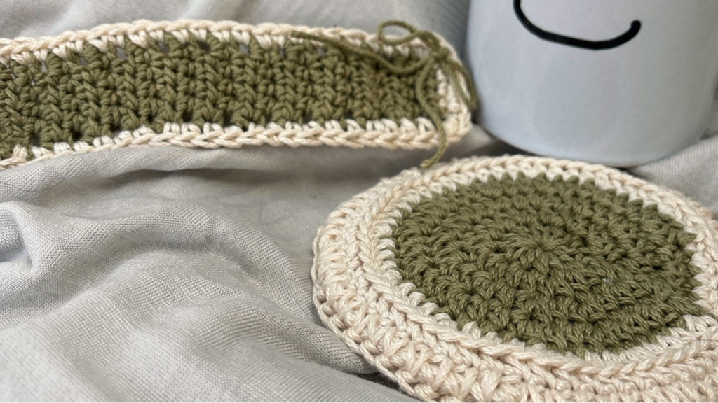 Crocheted coasters and a mug with a smiley face on a gray fabric background