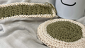Crocheted coasters and a mug with a smiley face on a gray fabric background