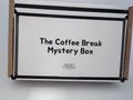 A white cardboard box labeled 'The Coffee Break Mystery Box' with 'Quiet Coffee Store' printed below, photographed on a light gray surface.